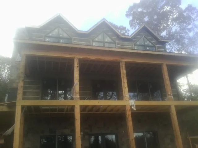 Dormers and porch framing on a large log home under construction — Roof Coating work by our crew in Key Biscayne