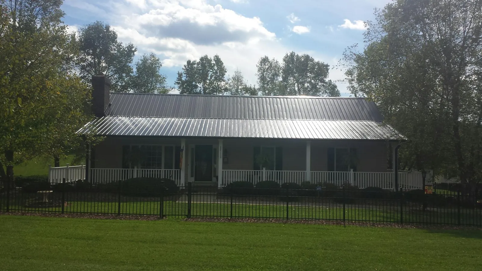 Gray metal roof on a brick ranch with a full width front porch — Gutter Guard Installation work by our crew in Key Biscayne